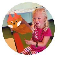 Young girl smiling with a homemade fox puppet on her right hand